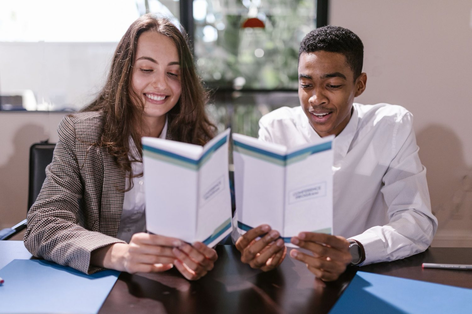 Two young professionals reading through a programme brochure together